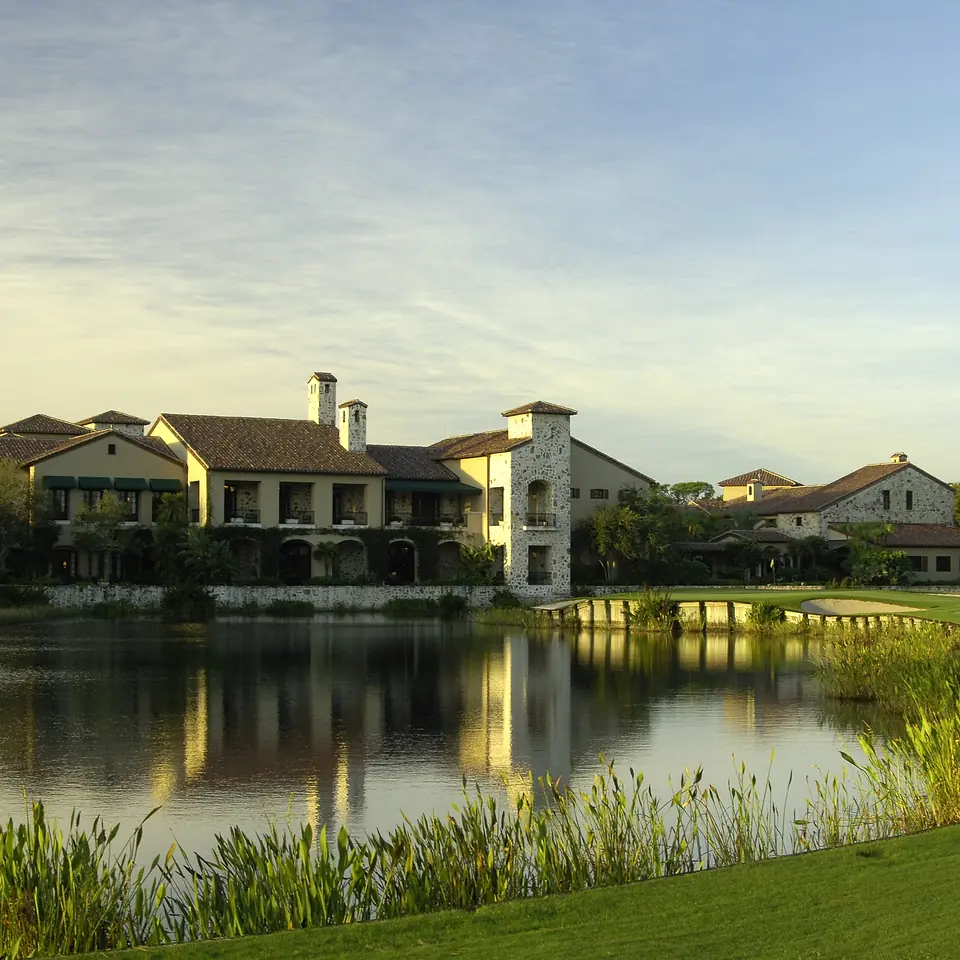 The Bear’s Club clubhouse reflected in a lake at dusk