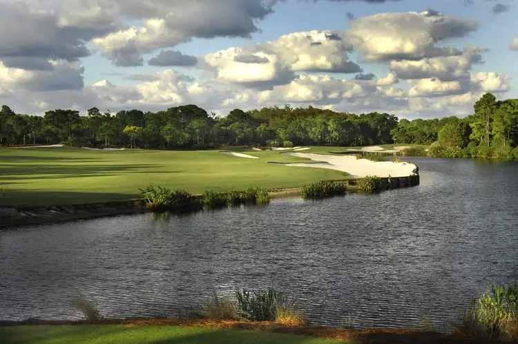 A green at The Bear’s Club set against the lake, pines on the far shore