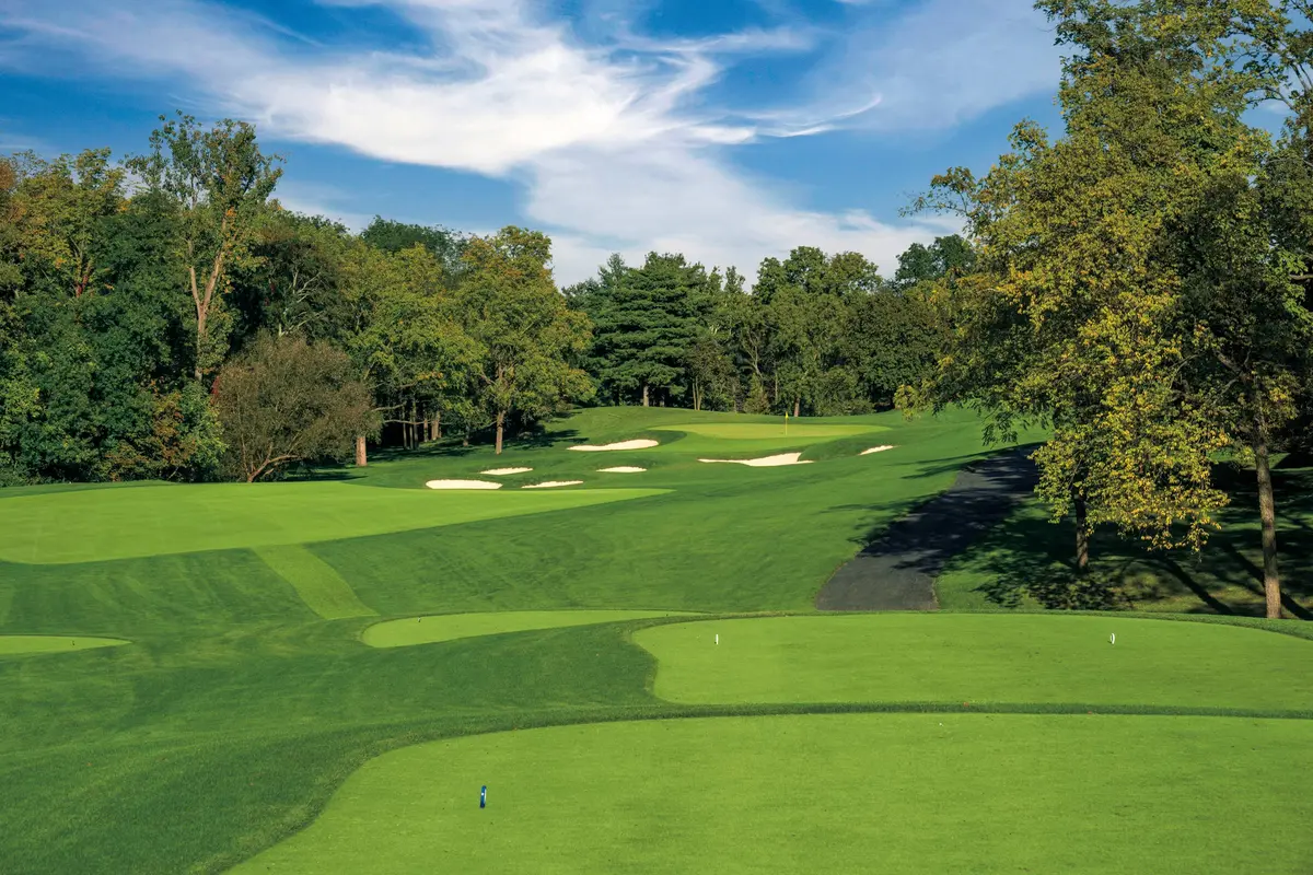 The first hole at Muirfield Village, a bunker guarding the fairway beneath tall oaks