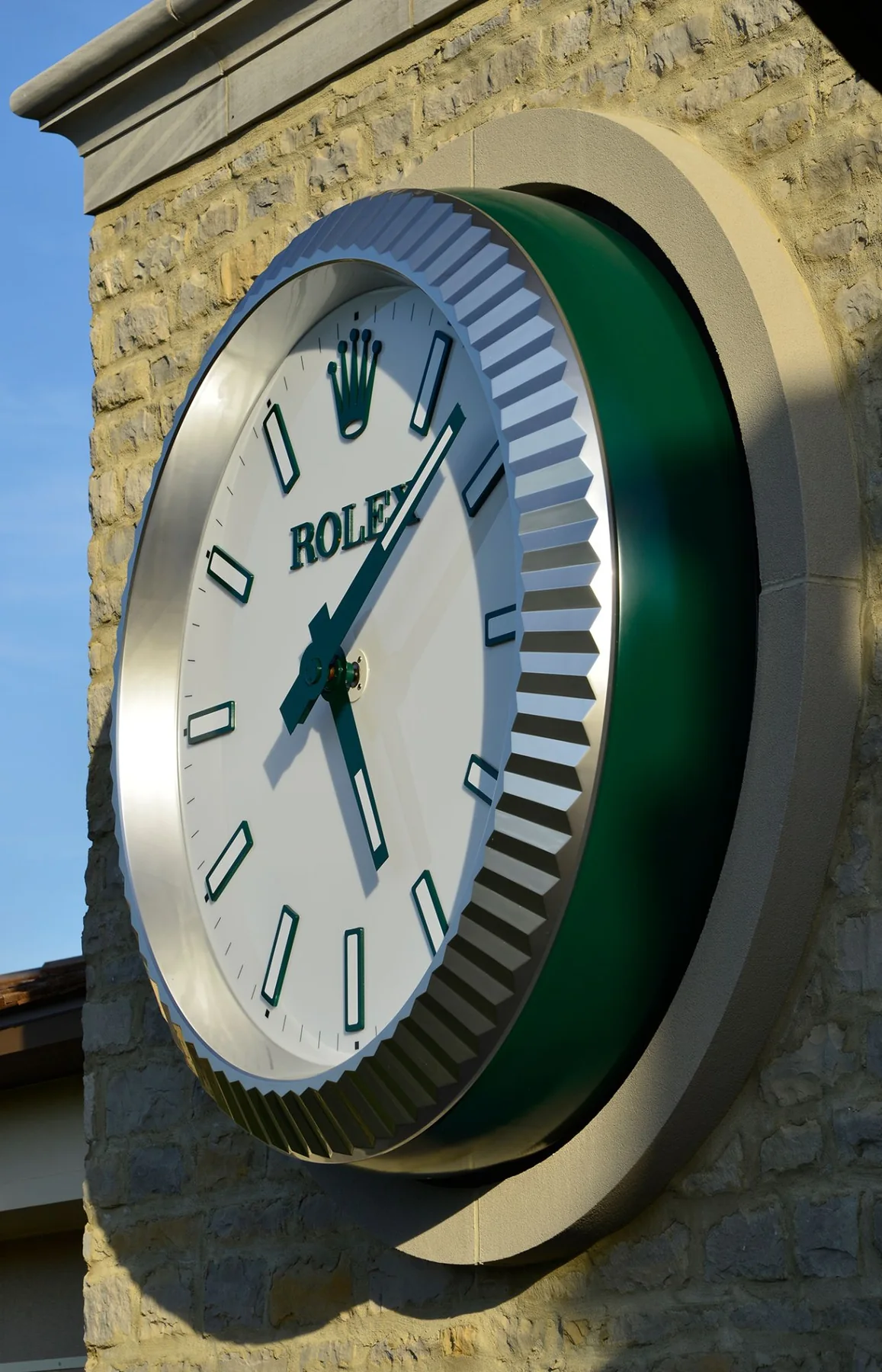 The tower clock up close: a white Rolex dial with green markers inside a fluted steel bezel