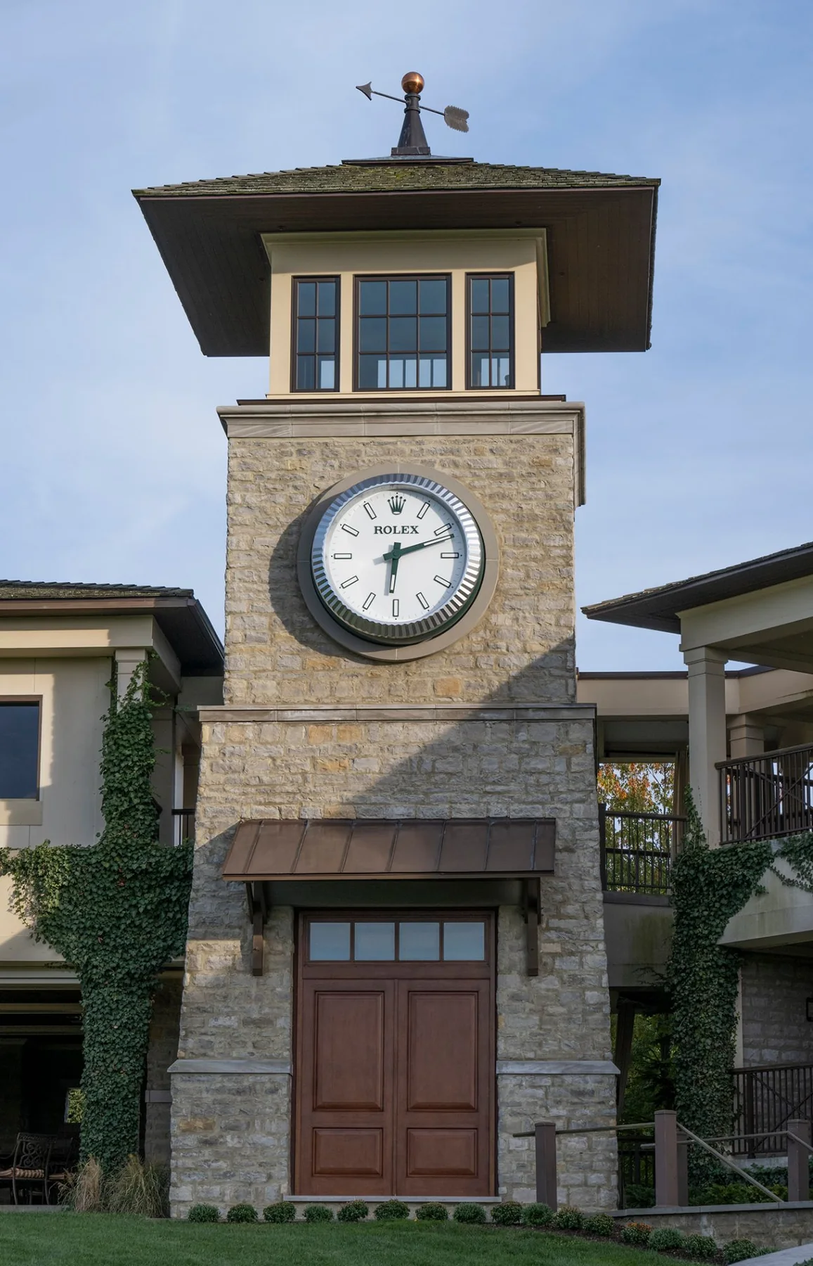 The stone clock tower above the clubhouse doors at Muirfield Village, a Rolex clock set in its face